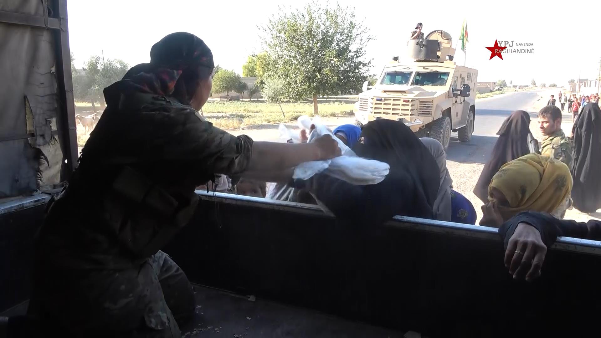 مقاتلو قوات سوريا الديمقراطية يوزعون مادة الخبز على الأهالي في دير الزور